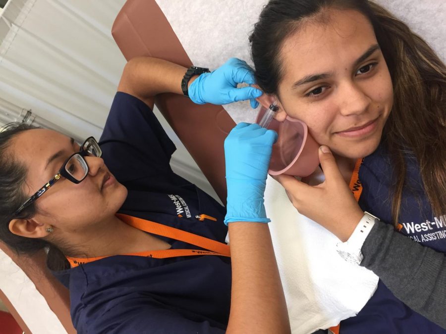 Senior Emily Estrada, left, performs a procedure on a fellow West-Mec student. Estrada is a student in the medical assisting program.